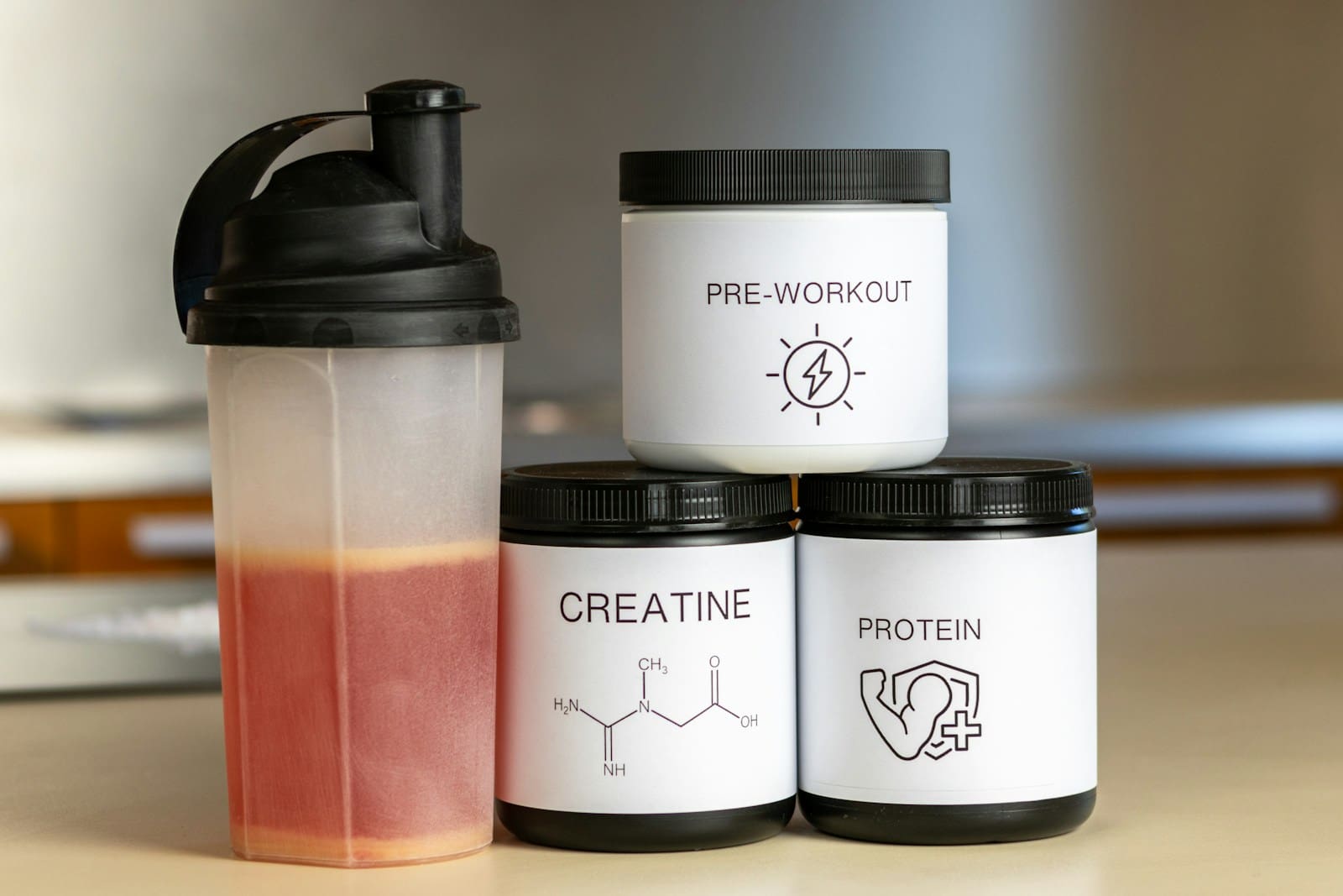 three containers of protein powder next to a blender