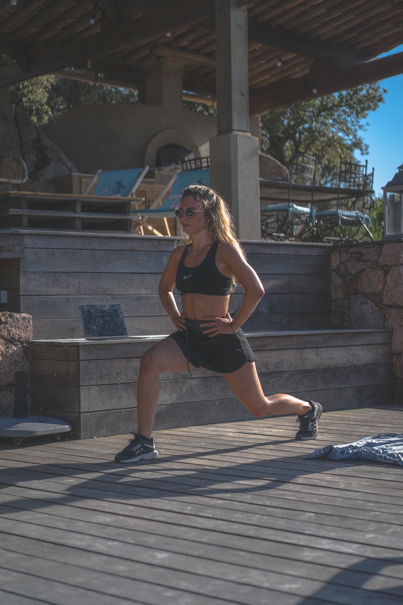 woman in black sports bra and black shorts sitting on concrete bench during daytime